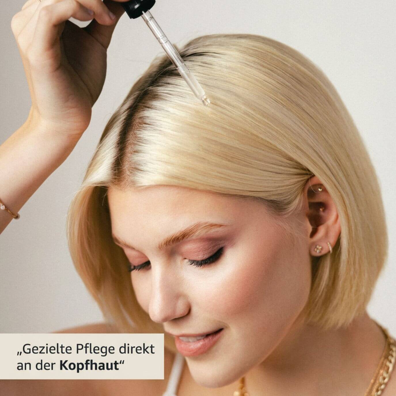 Frau mit blondem Bob trägt das Azerum Premium Kopfhautserum mit einer Glaspipette direkt auf den Scheitel auf – gezielte Pflege direkt an der Kopfhaut.