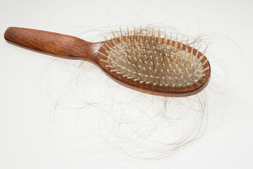 Haarbürste mit ausgefallenen Haaren als Symbol für Haarausfall und Haarverlust