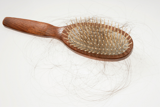 Haarbürste mit ausgefallenen Haaren als Symbol für Haarausfall und Haarverlust