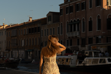 Frau mit vollem, glänzendem Haar im goldenen Abendlicht an einem Kanal in Venedig